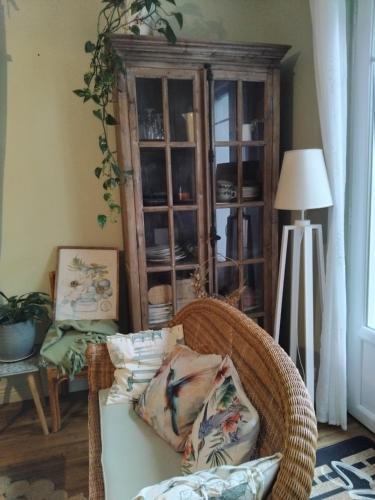 a living room with a wicker chair and a cabinet at Le jardin de Christine in Vinneuf