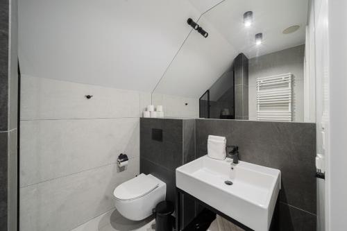 a bathroom with a white toilet and a sink at APT Nadmorskie - GreenPort z basenem i strefą SPA in Kołobrzeg