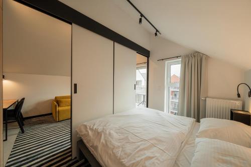 a bedroom with a large white bed and a window at APT Nadmorskie - GreenPort z basenem i strefą SPA in Kołobrzeg