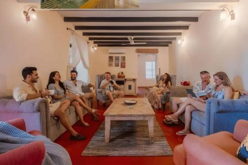 a group of people sitting in a living room at EKOSTAY Gold - Oasis Villa in Saligao