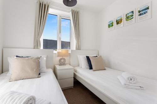 two beds in a room with two windows at Rigg & Rest Apartment - Bowness in Bowness-on-Windermere