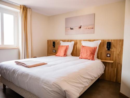 a bedroom with a large white bed with orange pillows at Baie Marine in Le Crotoy