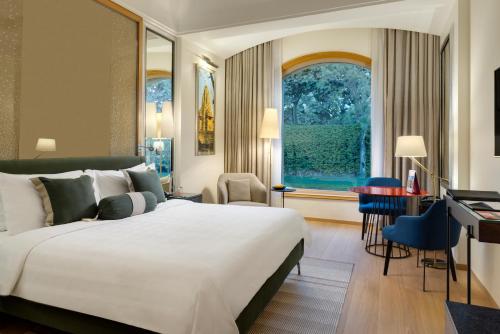 a hotel room with a large bed and a desk at Trident Gurgaon in Gurgaon