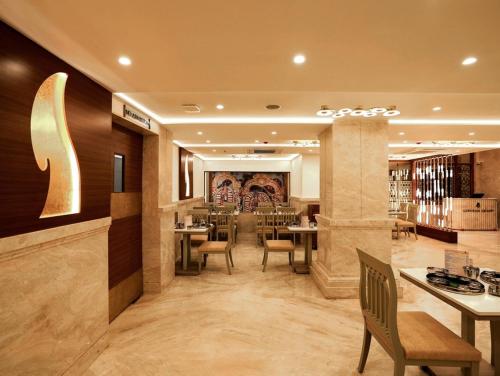 a restaurant with tables and chairs in a room at Gopuram Grand in Madurai
