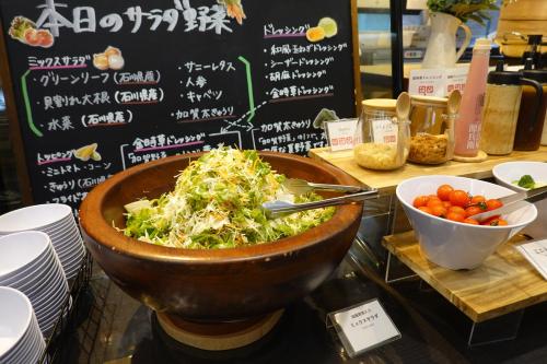 Un tazón de ensalada en un mostrador con un tazón de tomates. en APA Hotel Kanazawa Chuo, en Kanazawa