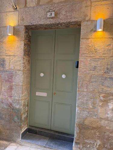 a green garage door in a stone wall with two lights at 3 St Anne's Street in Valletta