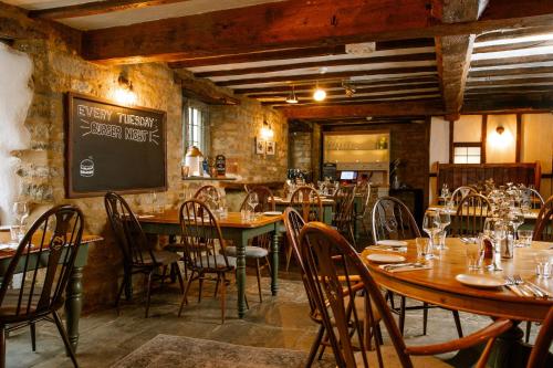 a restaurant with wooden tables and chairs and a chalkboard at The George Inn in Lower Brailes