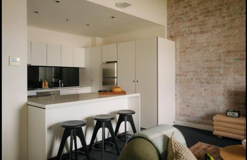 a kitchen with three bar stools and a counter at Gibson Mill Penthouse with private balcony - 301 in Hobart