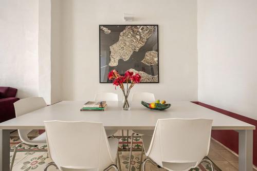 a white dining room table with white chairs and a vase of flowers at Heart of Valletta 2BR Apartment with Patio in Valletta