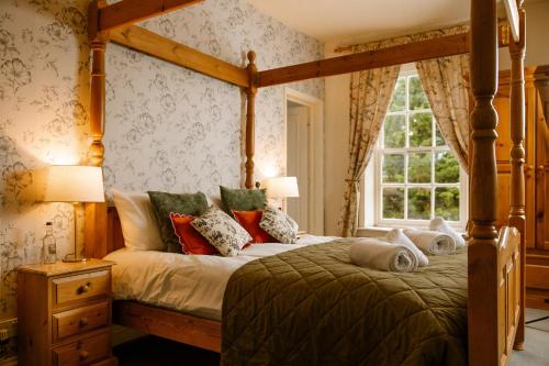 a bedroom with a canopy bed and a window at The George Inn in Lower Brailes