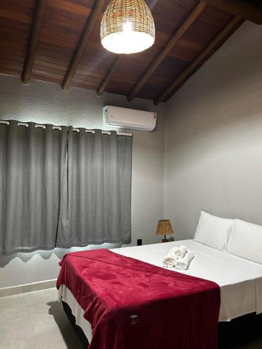 a bedroom with a bed with a red blanket on it at Casa da Sil in Arraial d'Ajuda