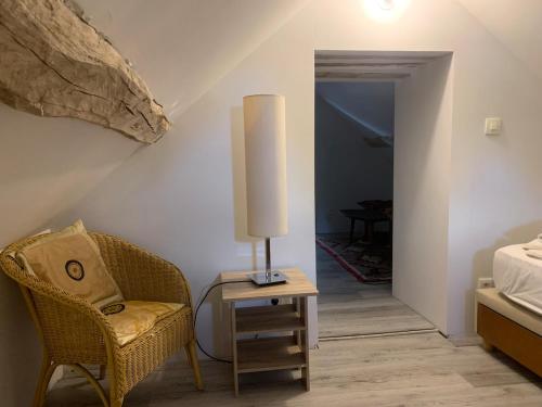 een slaapkamer met een stoel en een lamp op een tafel bij Domaine de Jarville in Aufferville