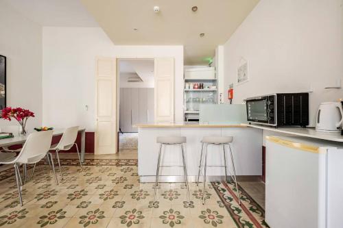 a kitchen with white counters and stools and a table at Heart of Valletta 2BR Apartment with Patio in Valletta
