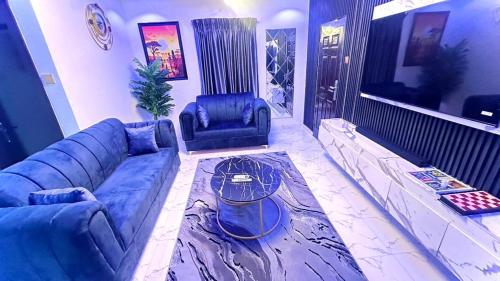 Una sala de estar con un sofá azul y un televisor. en Kunbiz Apartments, en Murtala Muhammed International Airport
