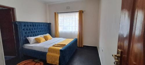 a bedroom with a blue bed and a window at Ashton cosy homes in Nakuru