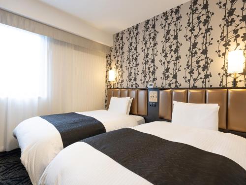 two beds in a hotel room with a wallpaper at APA Hotel Komatsu in Komatsu
