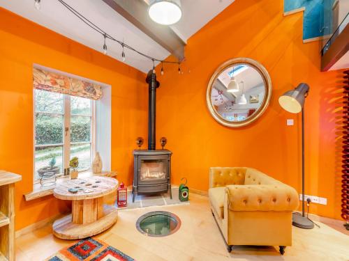 The Engine Room في مالهام: غرفة معيشة بجدران برتقالية وموقد خشبي