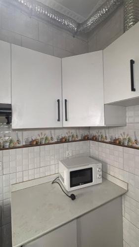Comfort Deluxe inn في كيغالي: مطبخ مع دواليب بيضاء وميكرويف على كونتر