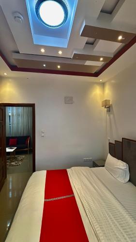 Comfort Deluxe inn في كيغالي: غرفة نوم بسرير وبطانية حمراء وبيضاء