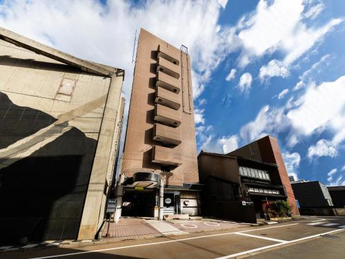a tall building on a street with a cloudy sky at APA Hotel Komatsu in Komatsu