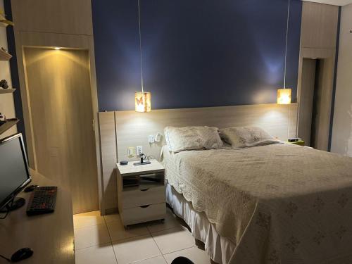 una camera da letto con un letto, una scrivania e una televisione di ACONCHEGANTE Quarto a Rio Verde