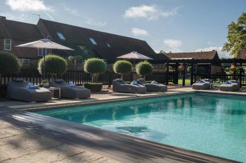 a swimming pool with lounge chairs and umbrellas in front of a house at Weston Cottage 4 in Send