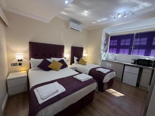 a hotel room with two beds and a kitchen at Crompton Guest House in Hounslow