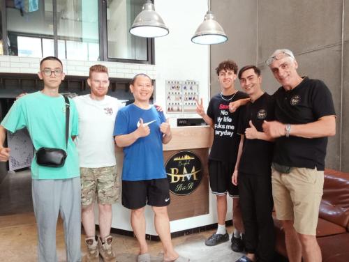 COZY Bangkok BM B&B في Amphoe Phra Khanong: مجموعة رجال واقفين امام طاولة