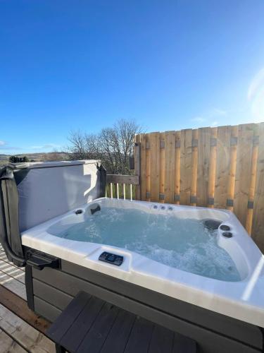 a jacuzzi tub on a deck with a fence at Kaoglen - Bali Pod - Hot Tub -Cairngorms - Pitlochry in Kirkmichael