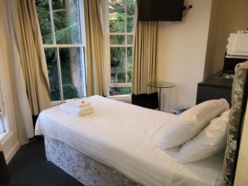 Un dormitorio con una cama con sábanas blancas y una ventana. en Nysdill Hotel Norwich, en Norwich