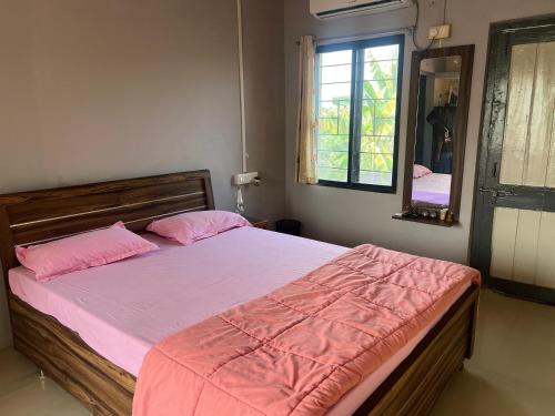 VISHWVRUND HOME STAy في Rājpīpla: غرفة نوم مع سرير وملاءات وردية ومرآة