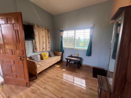 VISHWVRUND HOME STAy في Rājpīpla: غرفة معيشة مع أريكة ونافذة