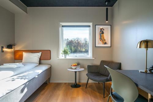 a bedroom with a bed and a chair and a window at MyHotel Taastrup in Tåstrup