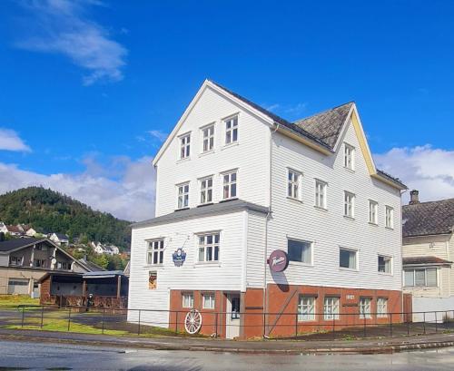 un grande edificio bianco sul lato di una strada di Sauda Bed & Breakfast a Sauda