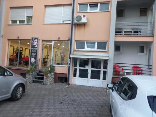 budynek z dwoma samochodami zaparkowanymi przed nim w obiekcie Apartman Rada 2 w mieście Bijeljina