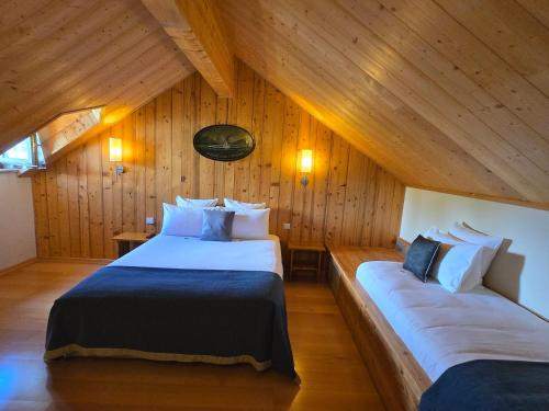 Hôtel La Riviera Victoria في إيفوار: سريرين في غرفة ذات جدران خشبية