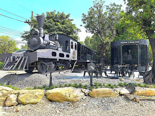 a train sitting on the tracks next to some tables at Khanom Station 549 in Khanom