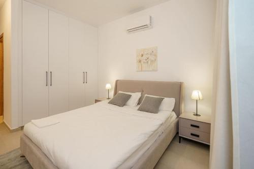 a white bedroom with a white bed and two lamps at Kalamon Luxury Suite 105 w Pool & Gym in Livadhia