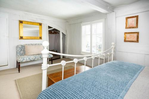 een witte slaapkamer met een bed en een stoel bij 3 Tudor Cottages in Long Melford
