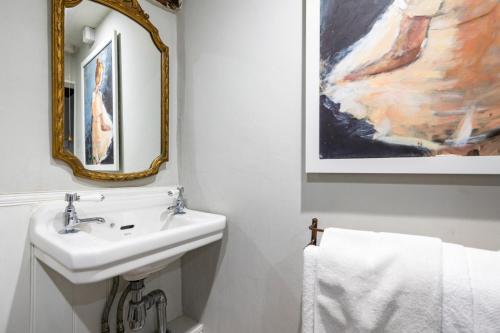 een witte badkamer met een wastafel en een spiegel bij 3 Tudor Cottages in Long Melford