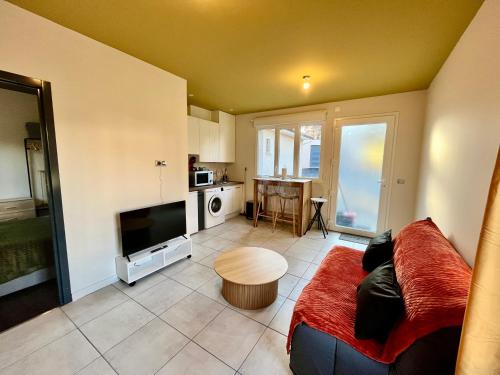 Gîte avec Terrasse et parking privé في Charnècles: غرفة معيشة مع أريكة وتلفزيون ومطبخ