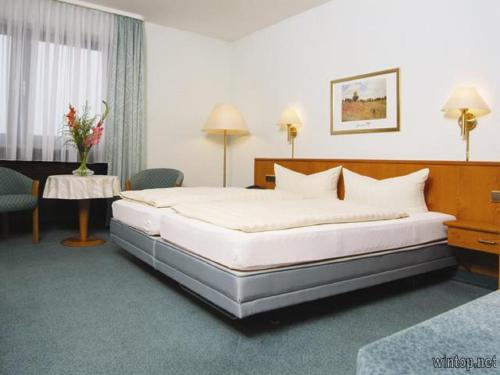 a bedroom with a large bed and a table at Gasthof-Hotel Maintal in Bad Staffelstein