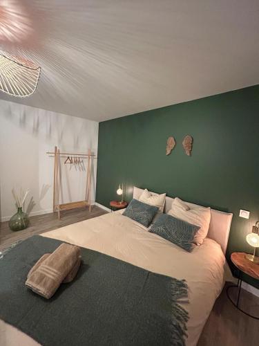 a bedroom with a large bed with a green wall at La maison du viaduc in Chauvigny