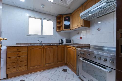 a kitchen with wooden cabinets and a sink and a stove at Havana Holiday Homes in Al Garhoud in Dubai
