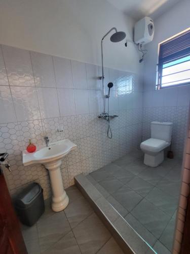 Un baño con lavabo, ducha e inodoro. en Tigris Residence, en Bulenga