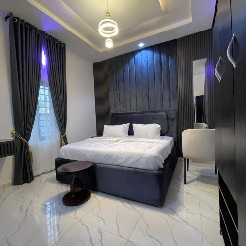 um quarto com uma cama grande com cabeceira preta em Garnet Apartments em Iyiba