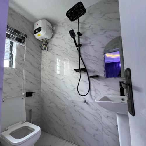 um banheiro branco com vaso sanitário e pia em Garnet Apartments em Iyiba