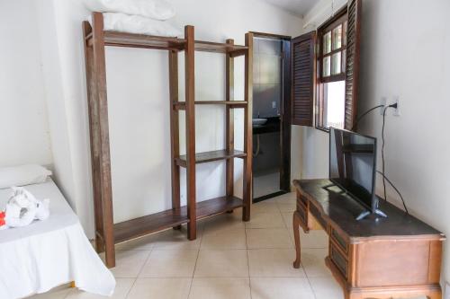 a room with a bed and a tv and a desk at Flat Flor da Terra in Itacaré