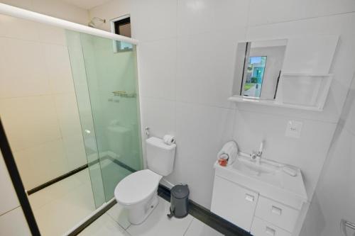 um banheiro com vaso sanitário e box de vidro em Pousada Oásis Tropical em Porto de Galinhas