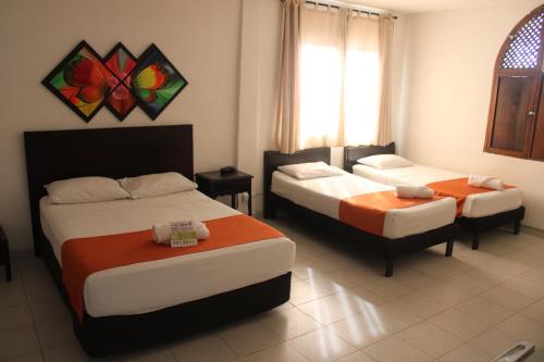 a room with three beds and a window and a room with two beds at Park Hotel in Santa Marta